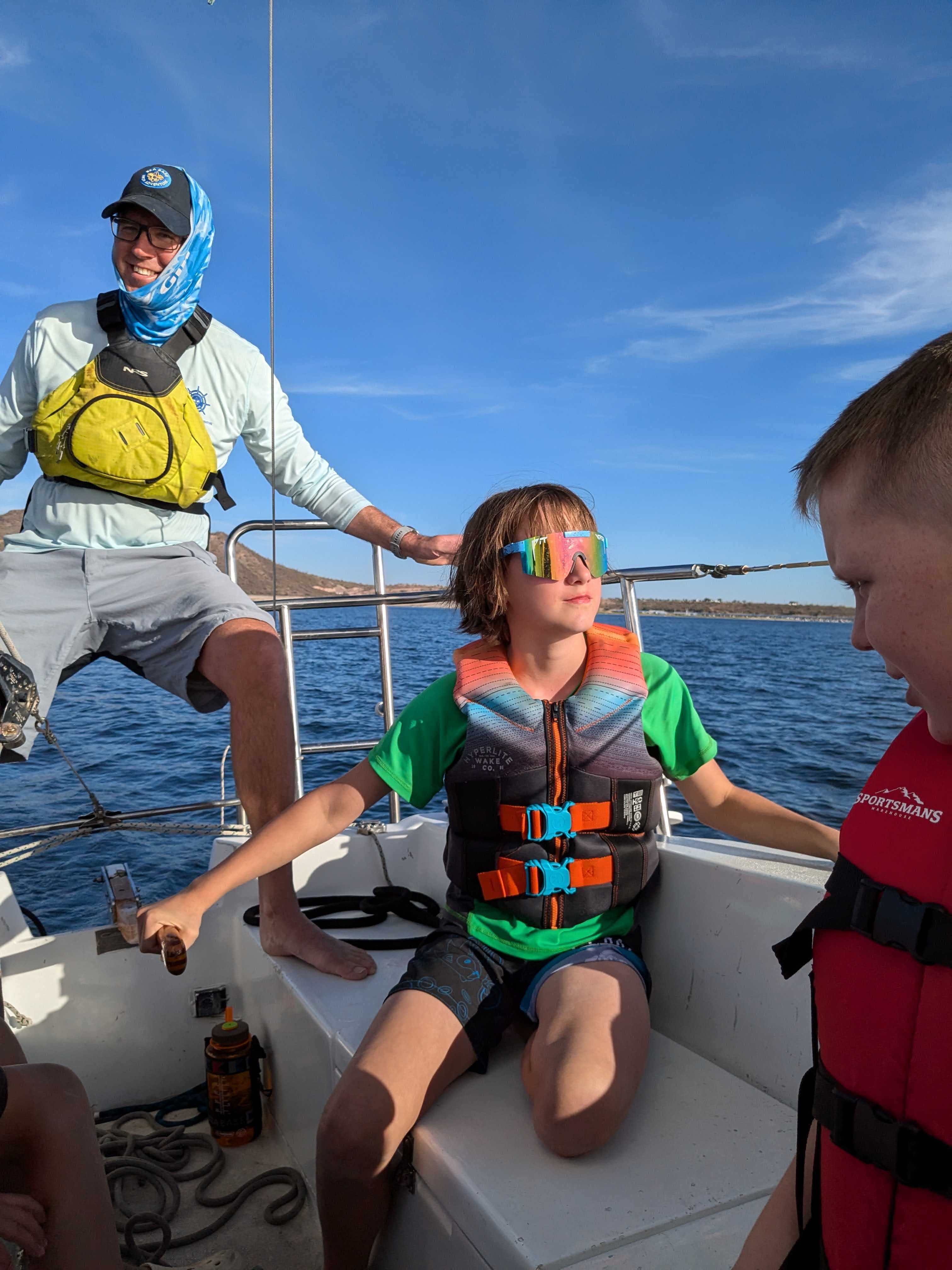 Man teaching child how to steer a sailboat